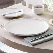 Het elegante Afina-dinerbord van 27,2 cm, gezien vanaf de zijkant op een gedekte tafel met bestek en servet.