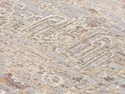 Nahaufnahme eines Designer Teppichs mit abstraktem Muster in Beige- und Grautönen, schräg von oben fotografiert.