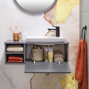 Modernes Waschtisch-Set mit grauem Schrank, weißem Waschbecken und schwarzem Wasserhahn, frontal fotografiert. Dekoriert mit Handtüchern, Zahnbürsten und Pflegeprodukten.