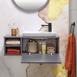 Modernes Waschtisch-Set mit grauem Schrank, weißem Waschbecken und schwarzem Wasserhahn, frontal fotografiert. Dekoriert mit Handtüchern, Zahnbürsten und Pflegeprodukten.