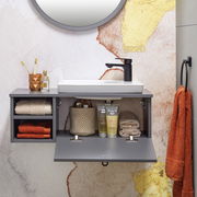 Modernes Waschtisch-Set mit grauem Schrank, weißem Waschbecken und schwarzem Wasserhahn, frontal fotografiert. Dekoriert mit Handtüchern, Zahnbürsten und Pflegeprodukten.