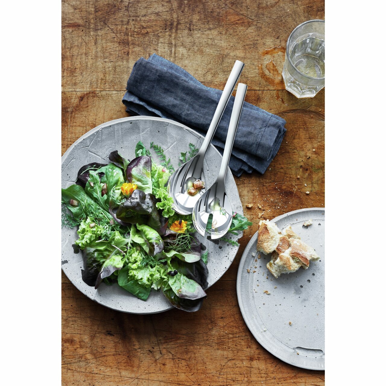 Salatbesteck NUOVA 25cm aus Edelstahl, auf einem Tisch mit einem frischen Salat in einer Schale, von oben fotografiert.