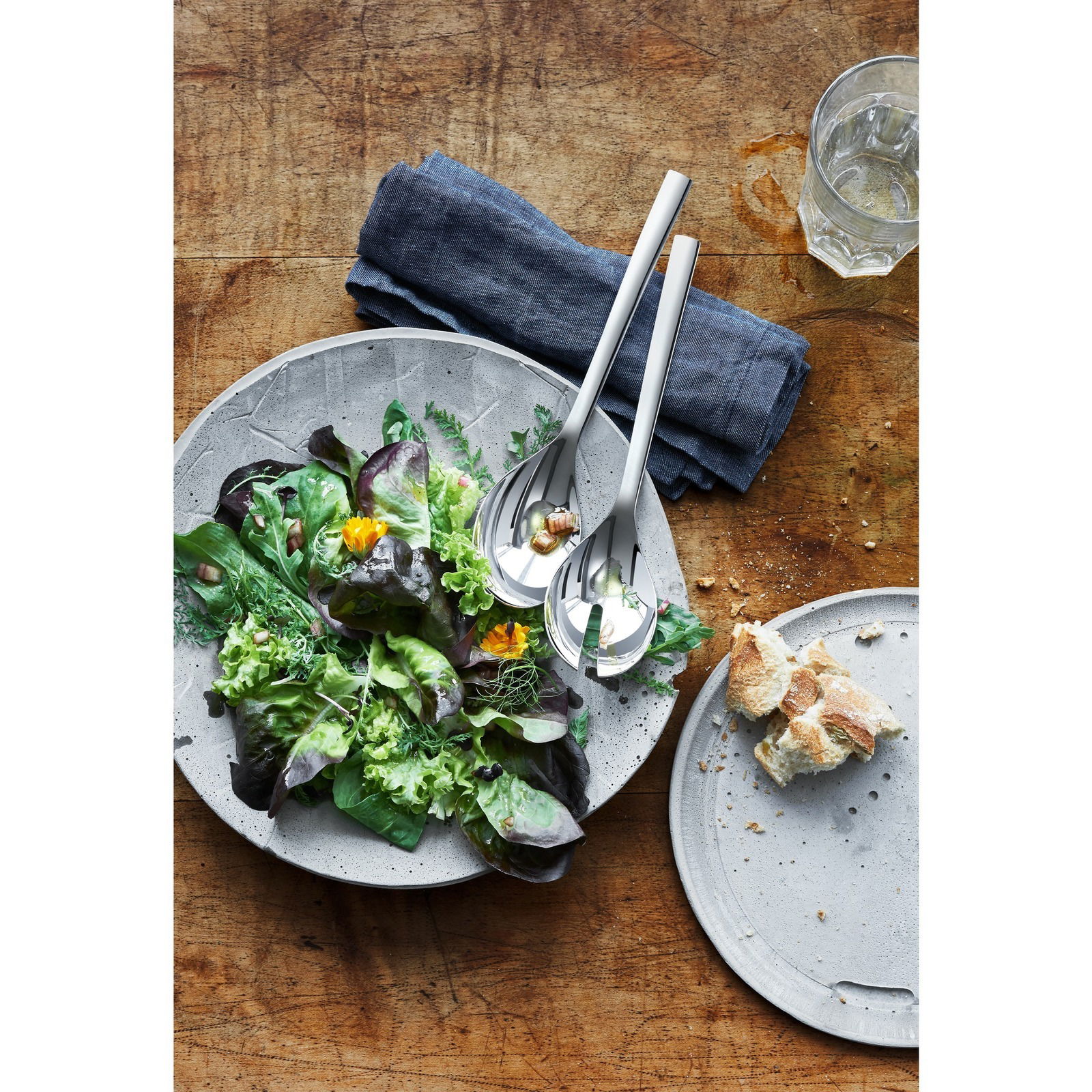 Salatbesteck NUOVA 25cm aus Edelstahl, auf einem Tisch mit einem frischen Salat in einer Schale, von oben fotografiert.