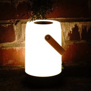 LED Laterne in Weiß und Grau, leuchtend in der Dunkelheit vor einer Ziegelwand, seitliche Perspektive