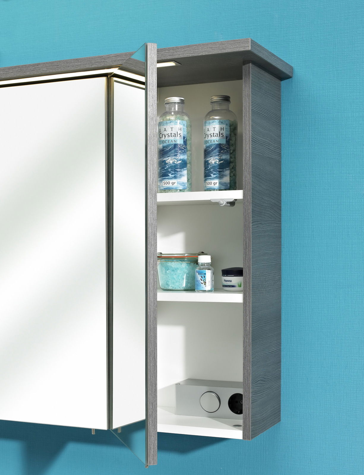 Spiegelschrank mit geöffneter Tür, zeigt Innenregale mit Badezusätzen, seitliche Perspektive