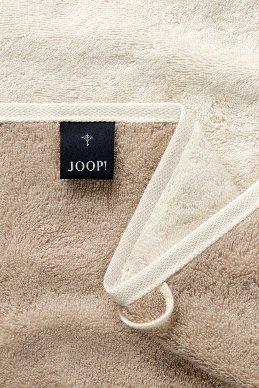 JOOP! Handtuch Nahaufnahme eines beigen Duschtuchs mit einem schwarzen Joop!-Etikett und einer Aufhängeschlaufe.
