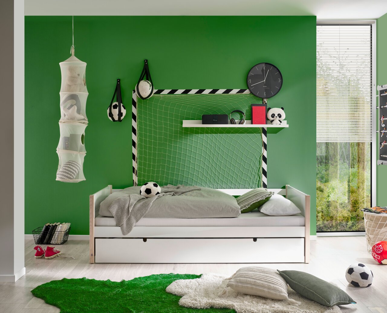 Jugendbett in einem sportlich dekorierten Zimmer mit grünem Fußballthema, seitliche Perspektive