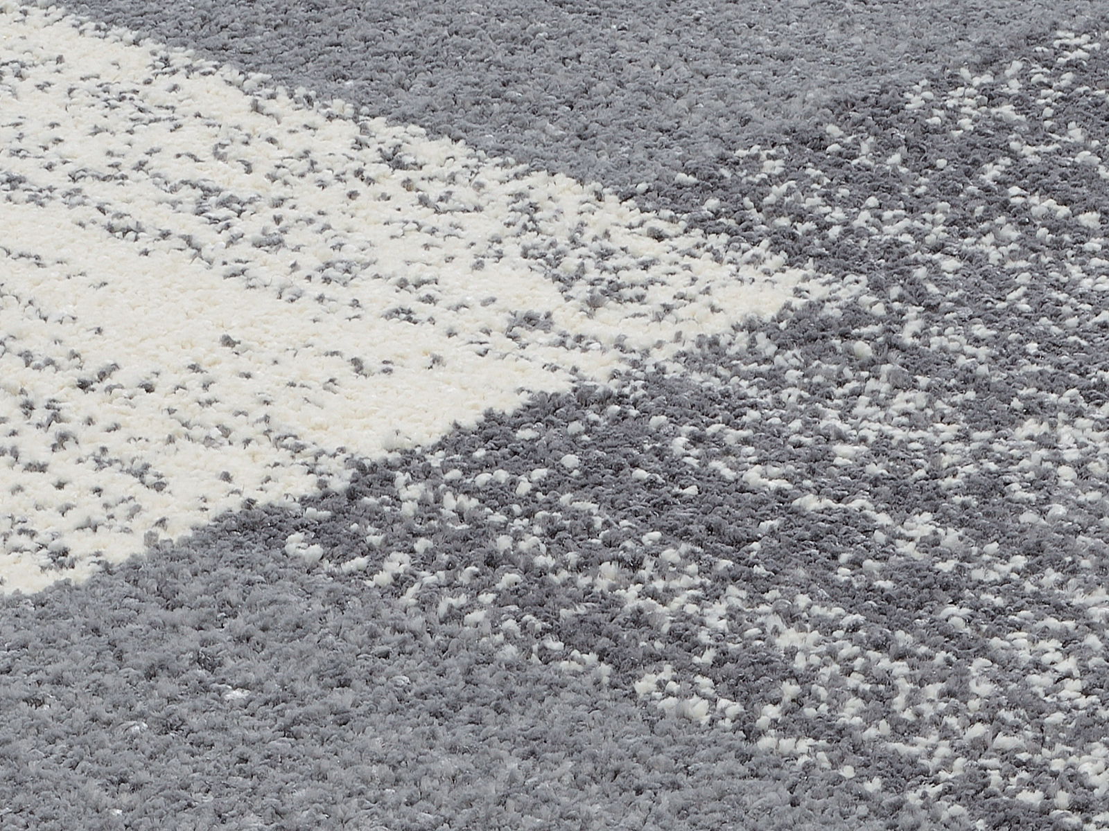 Nahaufnahme eines Frisé-Teppichs in Grau- und Weißtönen mit strukturierter Oberfläche.