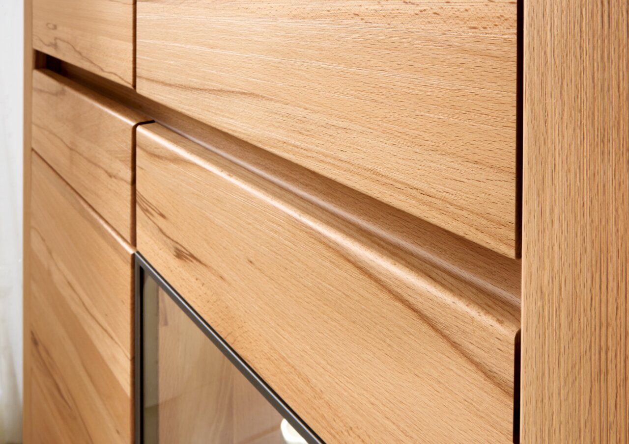 Nahaufnahme einer Wandkombination aus Holz mit glatter Oberfläche und Glasdetail, seitliche Perspektive.