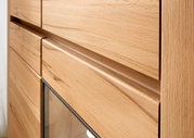 Nahaufnahme einer Wandkombination aus Holz mit glatter Oberfläche und Glasdetail, seitliche Perspektive.