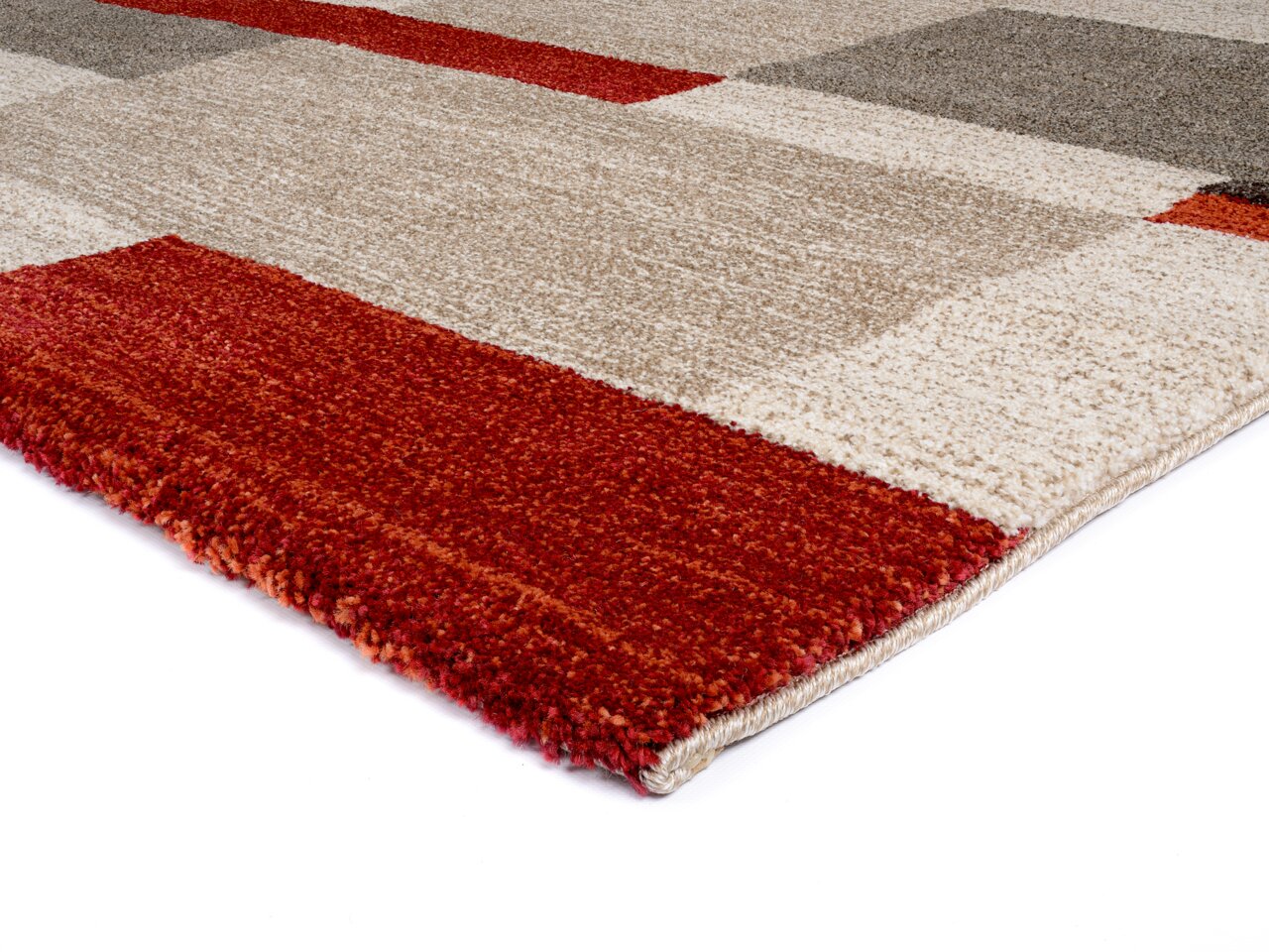 Nahaufnahme eines rechteckigen Teppichs mit geometrischem Muster in Rot-, Beige- und Grautönen, perspektivisch von der Seite aufgenommen.