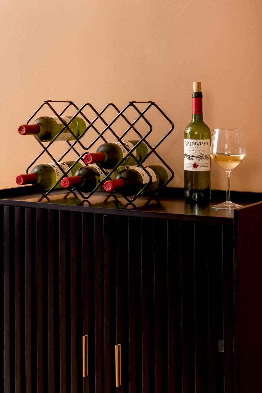 Weinregal aus Metall mit sechs Flaschen, auf einem schwarzen Schrank stehend, seitliche Perspektive