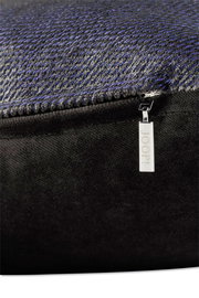 Nahaufnahme einer Zierkissenhülle mit feinem, strukturiertem Stoff in dunklen Tönen und einem silbernen Reißverschlussanhänger mit der Aufschrift 'JOOP!'.