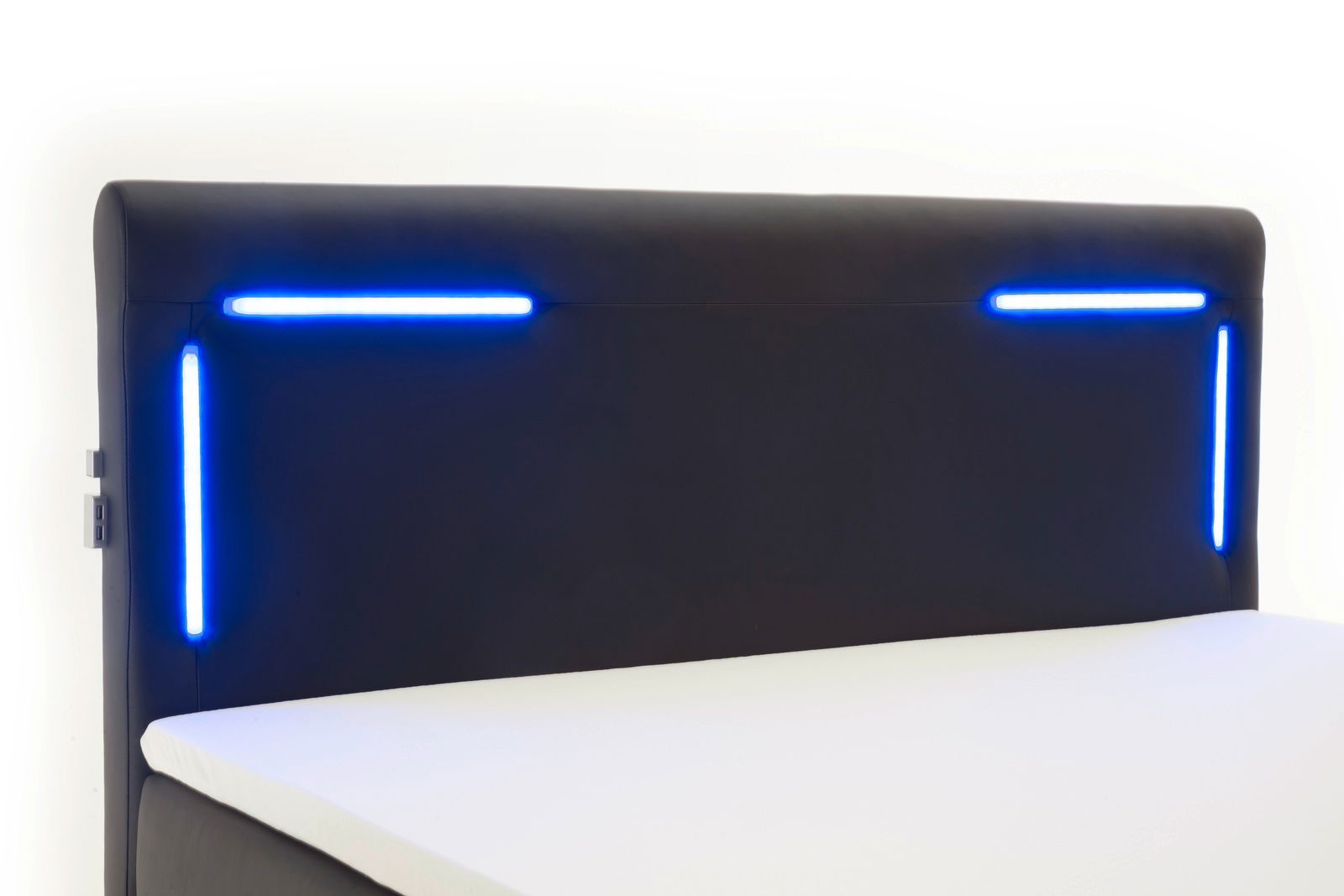 Boxspringbett mit modernem Kopfteil und blauer LED-Beleuchtung, seitliche Perspektive