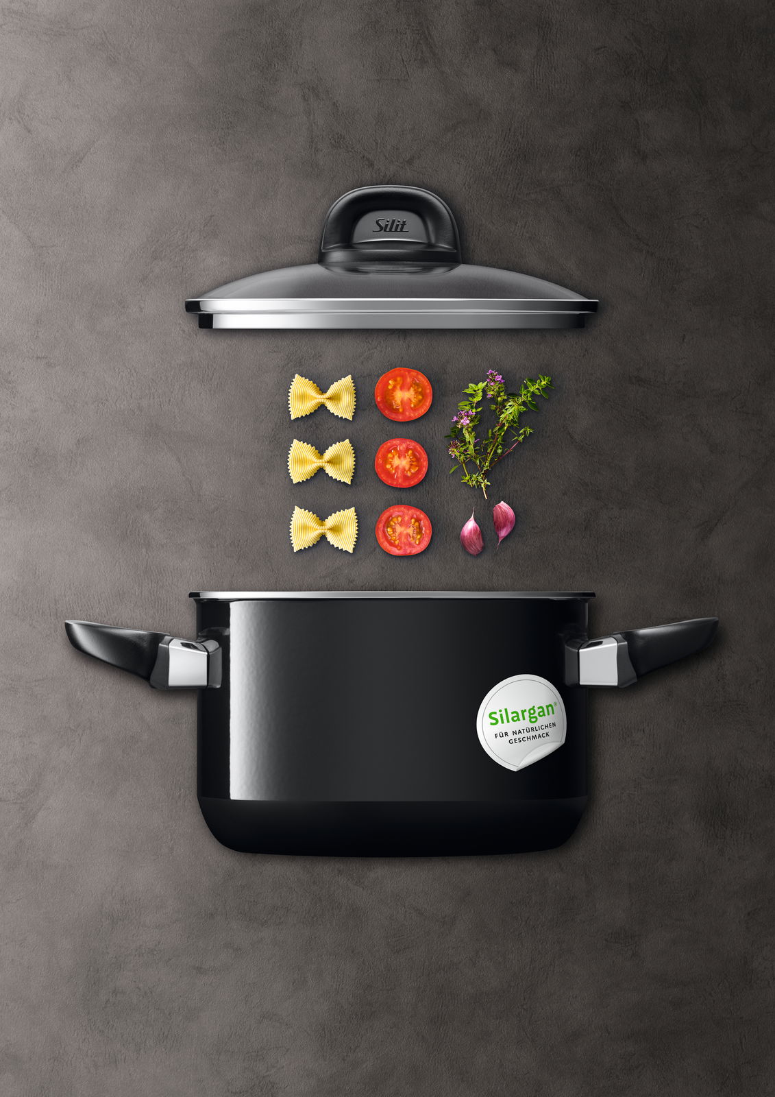 Topfset Modesto Line 4tlg. in schwarzer Farbe, von oben fotografiert, mit Zutaten wie Nudeln, Tomaten, Kräutern und Zwiebeln.