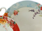 Zwei Porzellan-Teetassen mit Untertassen im floralen Vintage-Design, eine mit hellblauem Rand und eine mit rotem Rand, Nahaufnahme aus leicht schräger Draufsicht.