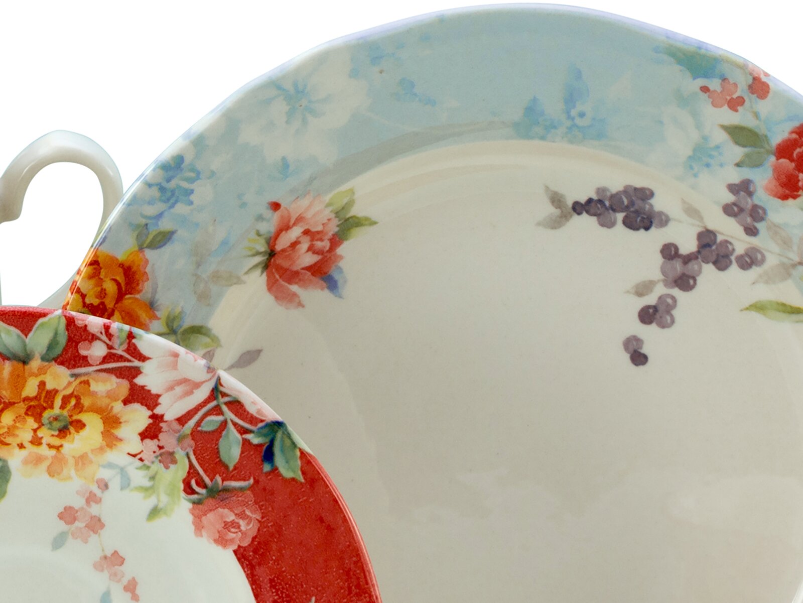 Zwei Porzellan-Teetassen mit Untertassen im floralen Vintage-Design, eine mit hellblauem Rand und eine mit rotem Rand, Nahaufnahme aus leicht schräger Draufsicht.