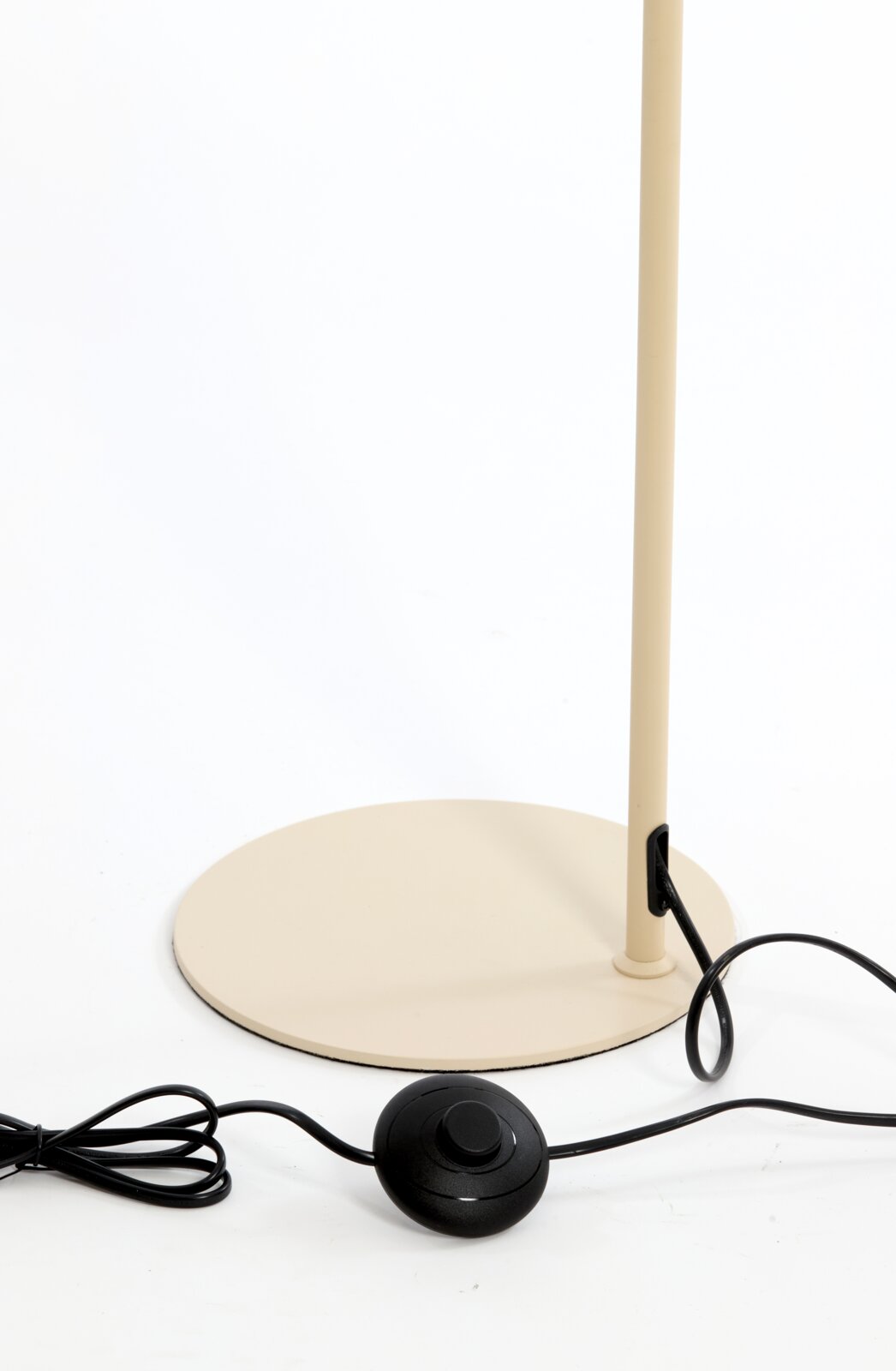 Detailaanzicht van de beige ronde lampvoet met slanke staander, zwart snoer en zwarte voetschakelaar, schuin van voren gefotografeerd
