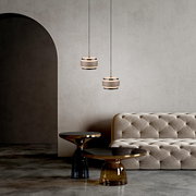 Zwei moderne LED-Pendelleuchten in einem eleganten Wohnzimmer mit einem beigen Sofa und stilvollen Beistelltischen, seitliche Perspektive.