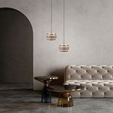 Zwei moderne LED-Pendelleuchten in einem eleganten Wohnzimmer mit einem beigen Sofa und stilvollen Beistelltischen, seitliche Perspektive.