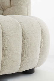 Nahaufnahme einer beigen Couch mit strukturierter Polsterung und abgerundeten Formen, seitliche Perspektive