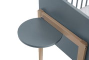 Ronde, grijze houten plank, aan de zijkant van een meubelstuk bevestigd, gezien vanuit vogelperspectief.