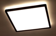 Quadratische LED-Deckenleuchte mit schwarzem Rahmen, von unten betrachtet, leuchtet hell an der Decke.