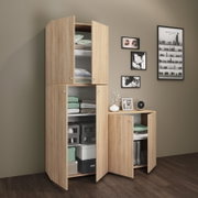 Hoher Mehrzweckschrank in heller Eichenoptik mit mehreren geöffneten Türen, sichtbar sind Regalböden mit gefalteten Textilien und Aufbewahrungsboxen; Ansicht schräg von vorn