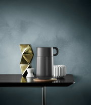 Impulse Travel Mug 0,3 l Cromar in zijaanzicht op een tafel, omringd door decoratieve voorwerpen.
