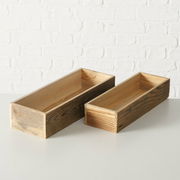 Zwei rechteckige Holzkisten auf einer weißen Oberfläche vor einer weißen Ziegelwand, aus leicht erhöhter Perspektive fotografiert.