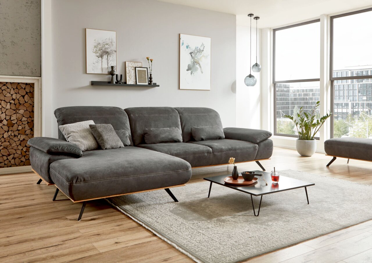 Graue Longchairkombination in modernem Wohnzimmer mit Holzfußboden, dekorativen Kissen und Couchtisch, seitliche Perspektive.