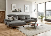Graue Longchairkombination in modernem Wohnzimmer mit Holzfußboden, dekorativen Kissen und Couchtisch, seitliche Perspektive.