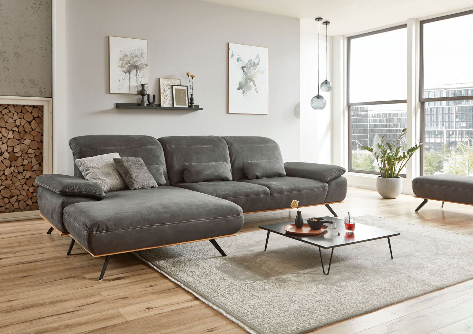 Graue Longchairkombination in modernem Wohnzimmer mit Holzfußboden, dekorativen Kissen und Couchtisch, seitliche Perspektive.