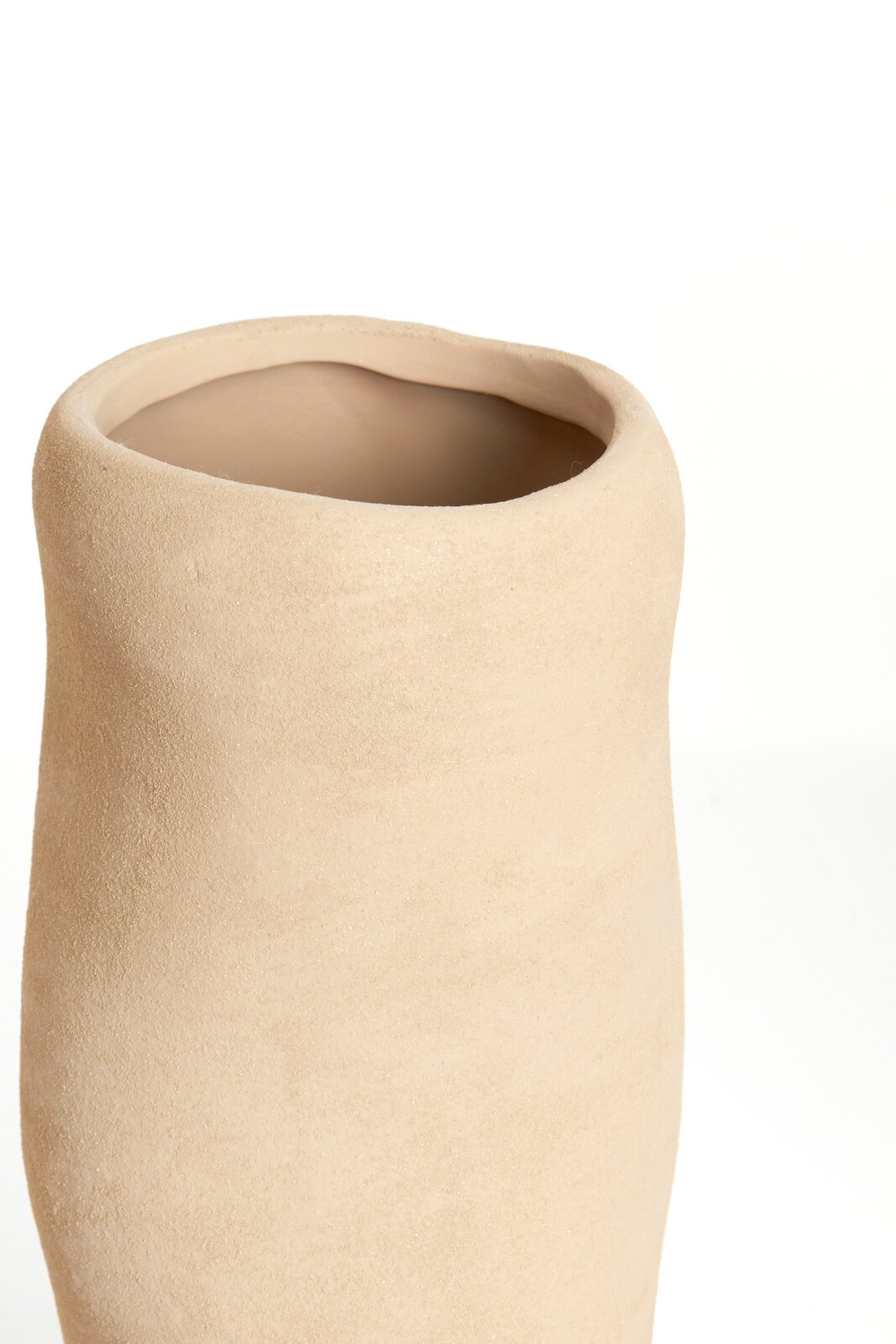 Nahaufnahme einer schlichten, beigen Vase mit unregelmäßiger Form und rauer Oberfläche, von oben betrachtet.