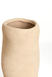 Nahaufnahme einer schlichten, beigen Vase mit unregelmäßiger Form und rauer Oberfläche, von oben betrachtet.