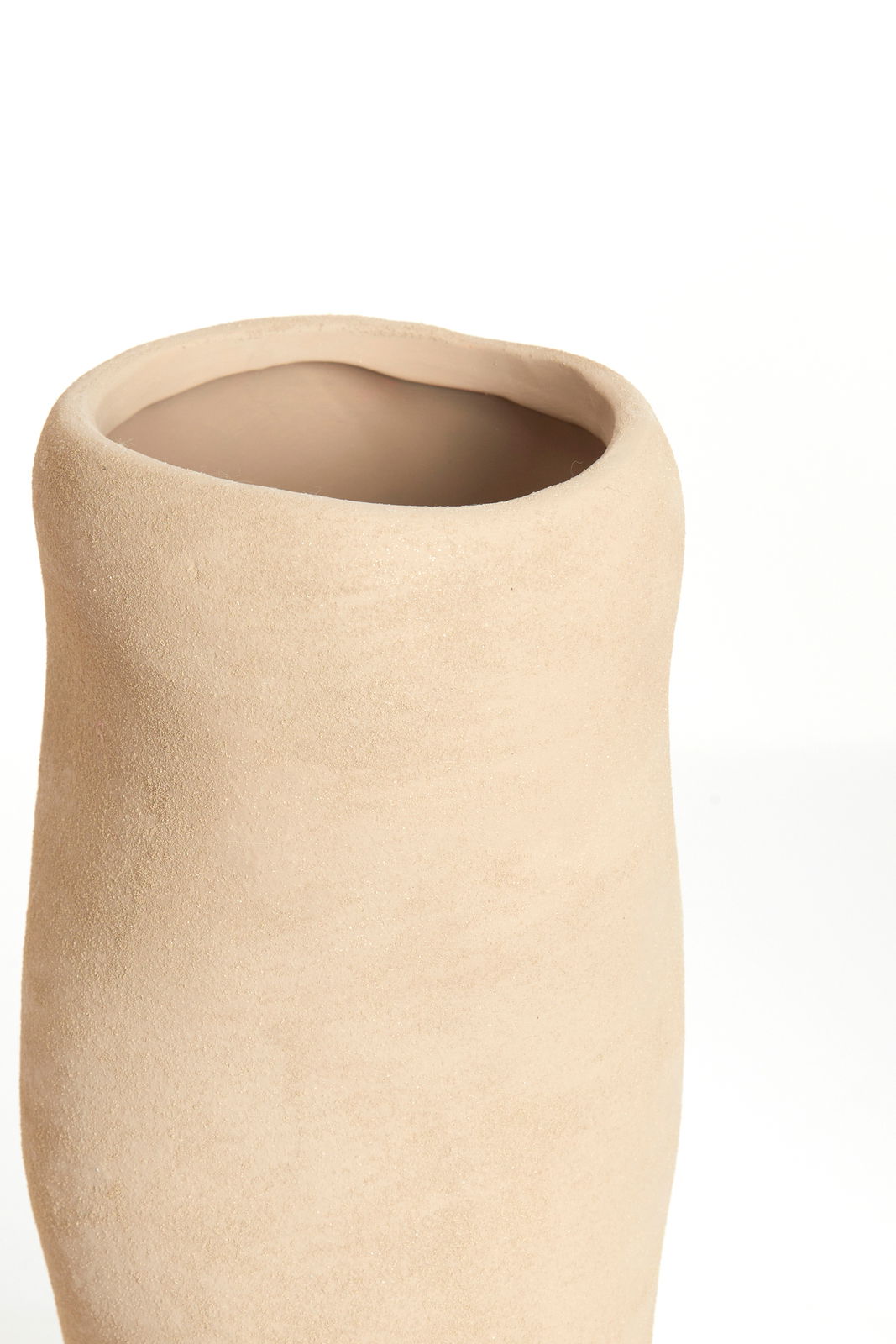 Nahaufnahme einer schlichten, beigen Vase mit unregelmäßiger Form und rauer Oberfläche, von oben betrachtet.