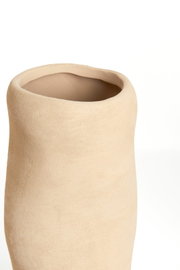 Close-up van een eenvoudige, beige vaas met een onregelmatige vorm en een ruw oppervlak, gezien van bovenaf.