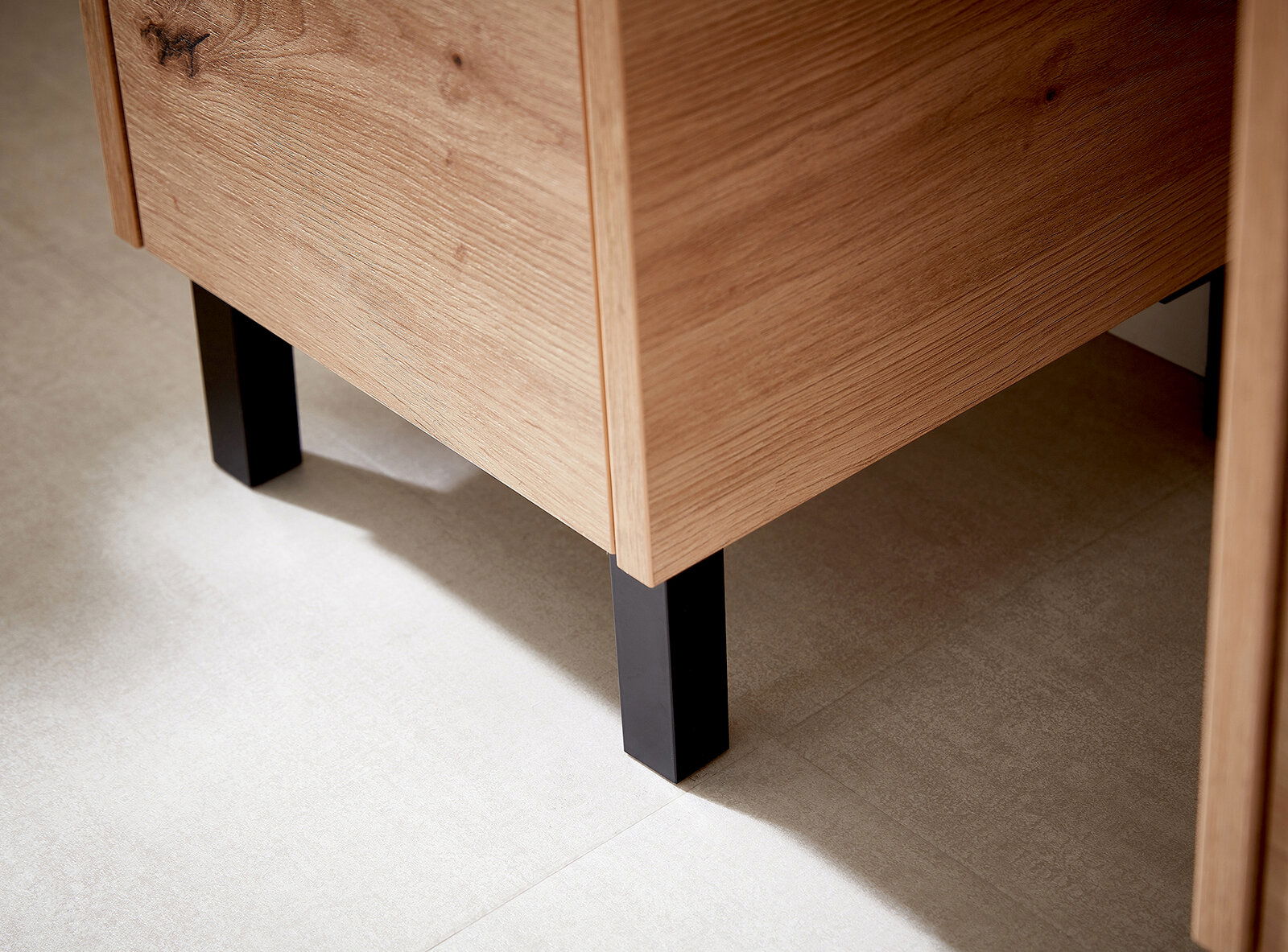 XORA Fuß-Set, 2-teilig XO1000 Nahaufnahme eines Möbelstücks mit Holzoberfläche und schwarzen Metallfüßen, seitliche Perspektive
