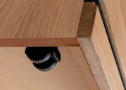 Nahaufnahme einer Roll-Kommode aus Holz mit schwarzem Rad, von unten betrachtet.