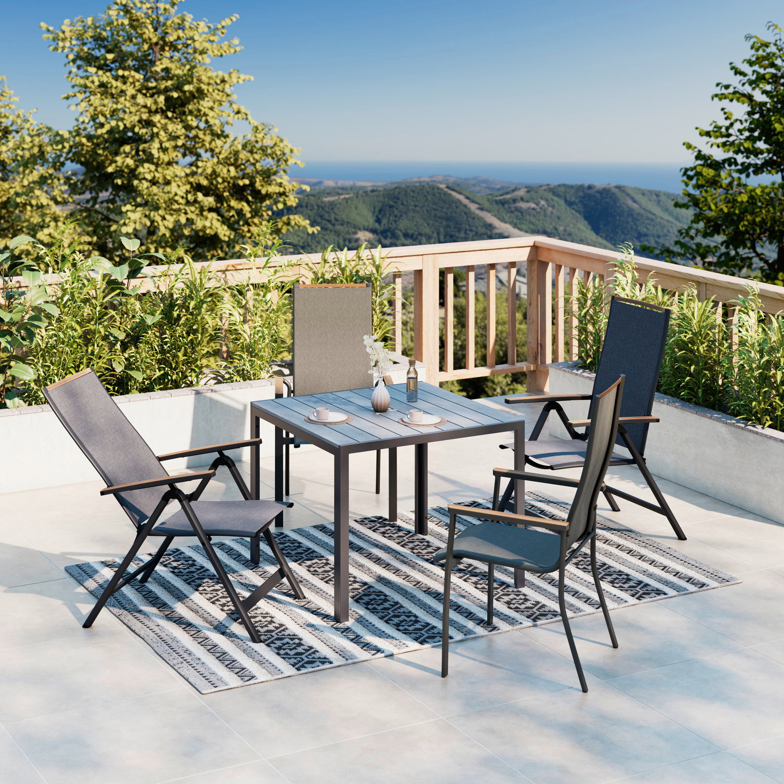 Ambia Garden Tuintafel 80x80 VALENCIA Moderner Gartentisch auf einer Terrasse mit Blick auf die Berge, umgeben von vier Stühlen und dekoriert mit Geschirr und einer Vase. Perspektive von schräg oben.
