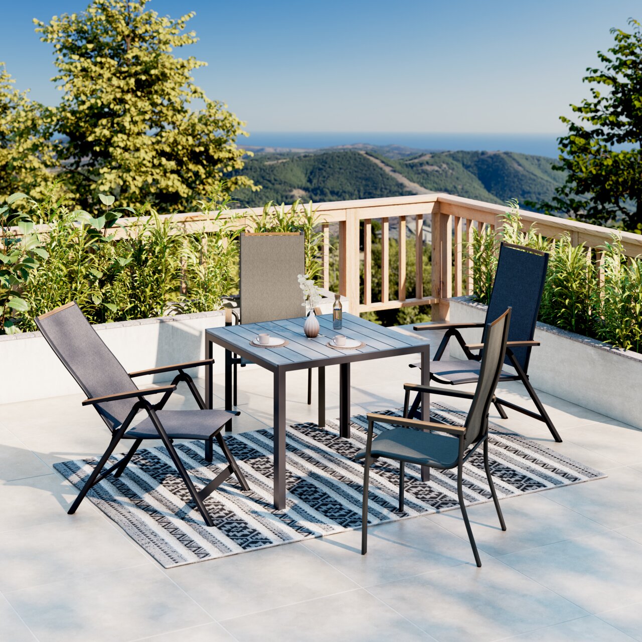 Een moderne tuintafel op een terras met uitzicht op de bergen, omringd door vier stoelen en versierd met serviesgoed en een vaas. Perspectief vanuit een schuine hoek van bovenaf.