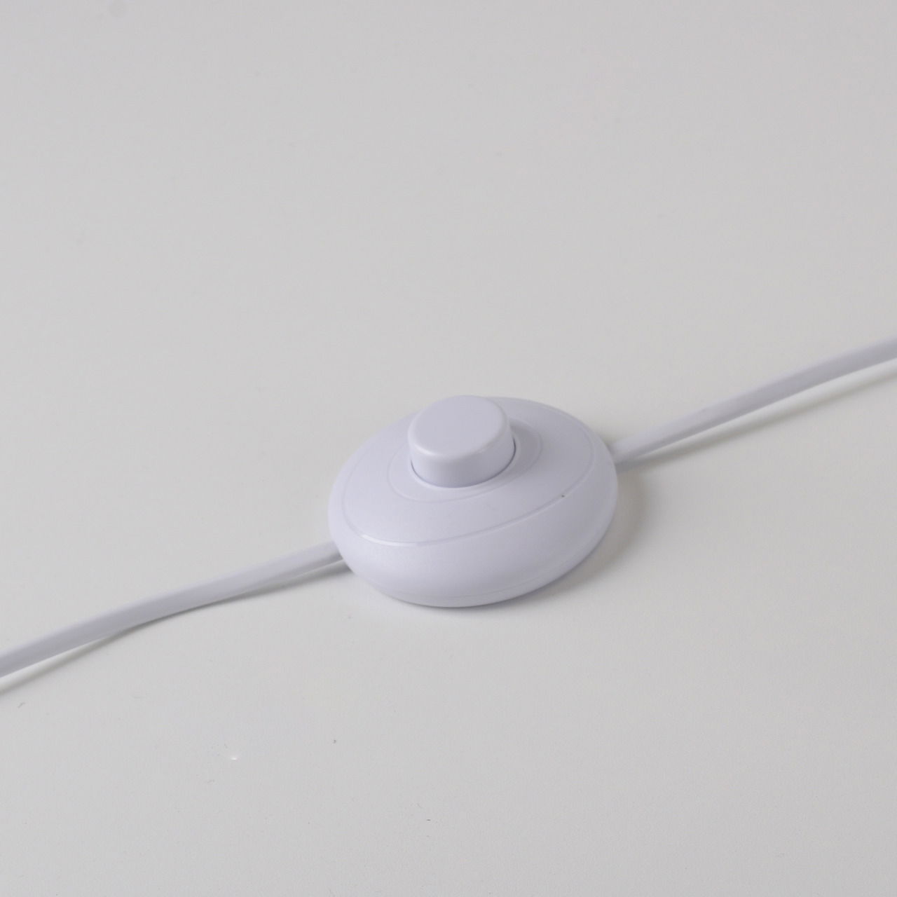 Nahaufnahme eines weißen Fußschalters für die Stehleuchte LOLAsmart-NAOMI auf einer weißen Oberfläche.