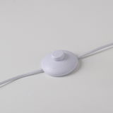 Nahaufnahme eines weißen Fußschalters für die Stehleuchte LOLAsmart-NAOMI auf einer weißen Oberfläche.