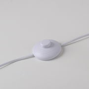 Nahaufnahme eines weißen Fußschalters für die Stehleuchte LOLAsmart-NAOMI auf einer weißen Oberfläche.