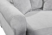 Nahaufnahme einer grauen, gerippten Sofaecke mit Armlehne und Kissen, seitliche Perspektive.