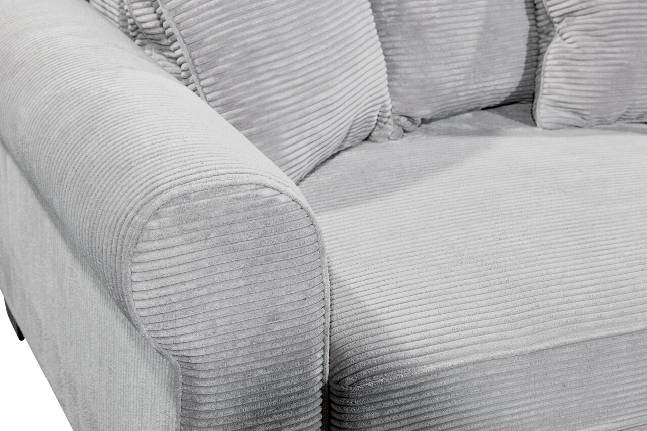 Nahaufnahme einer grauen, gerippten Sofaecke mit Armlehne und Kissen, seitliche Perspektive.
