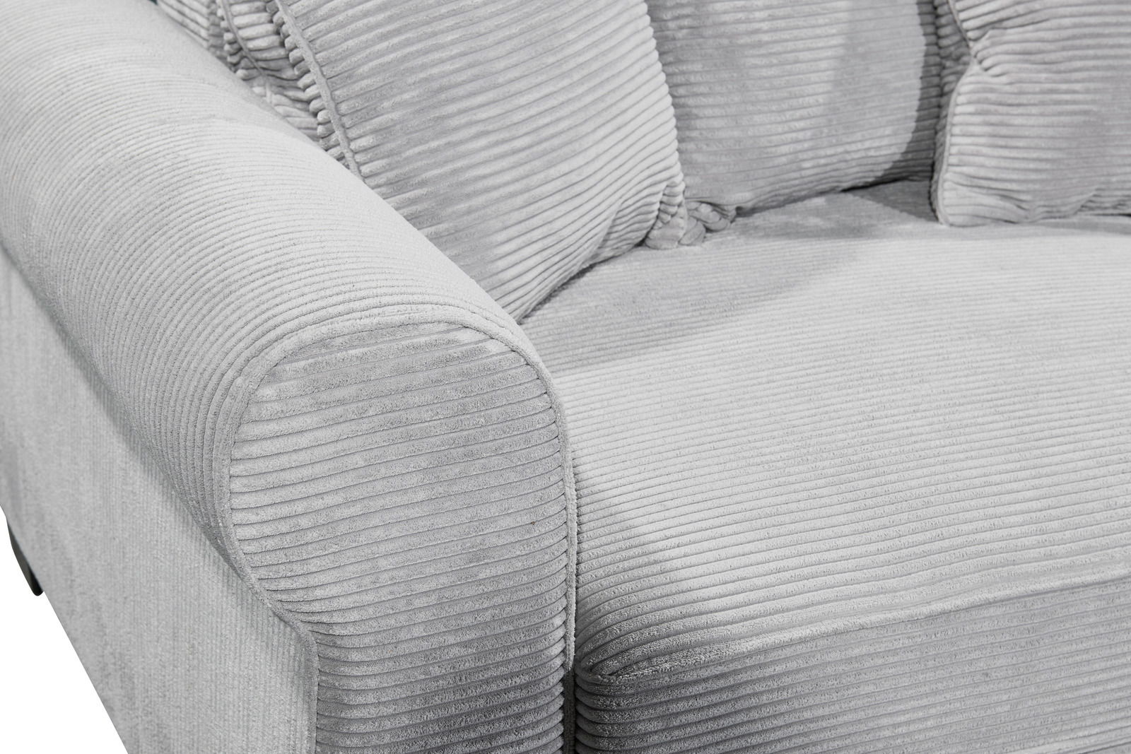 Nahaufnahme einer grauen, gerippten Sofaecke mit Armlehne und Kissen, seitliche Perspektive.