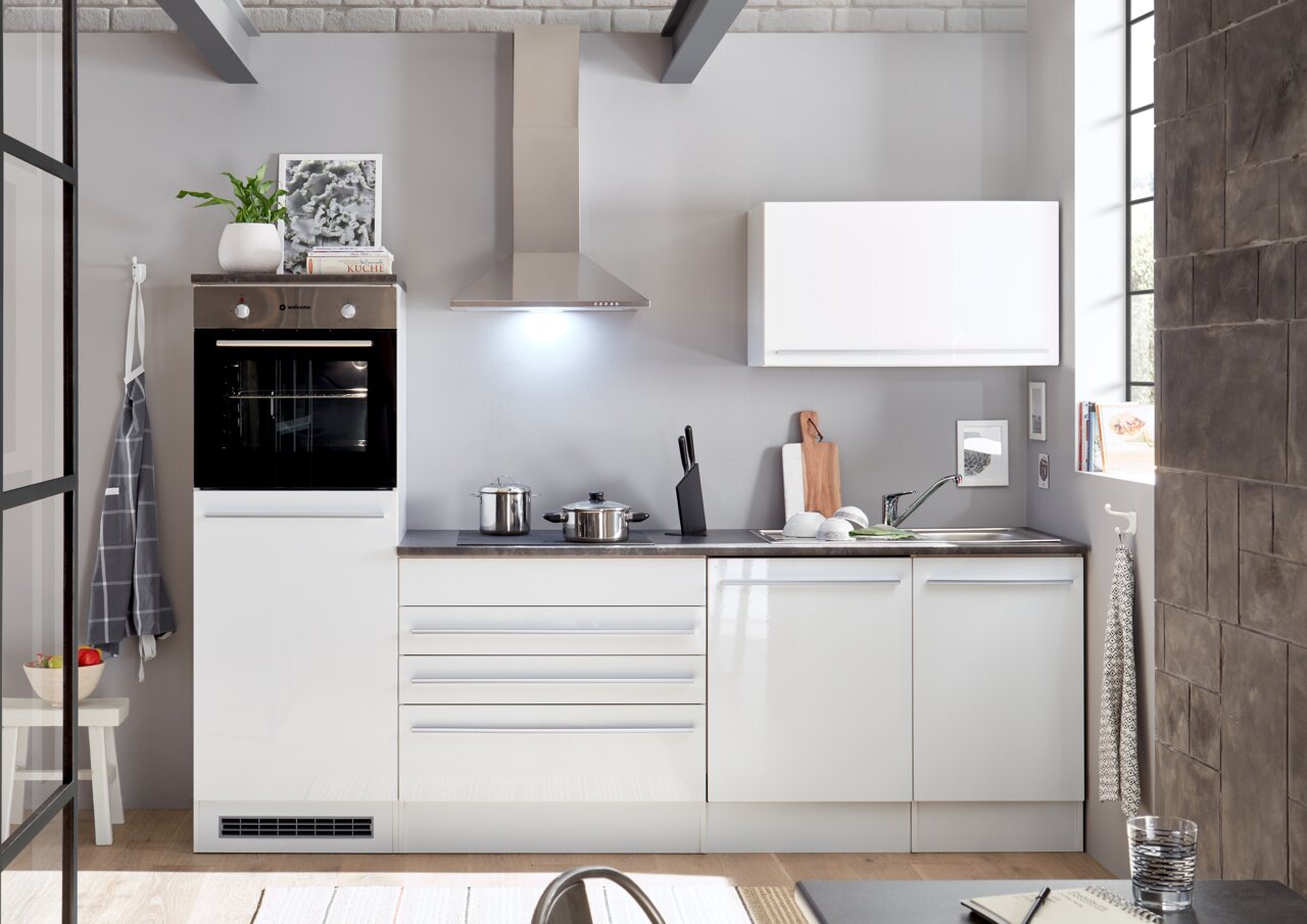 Moderne Küchenzeile mit weißem Hochglanzfinish, eingebautem Backofen, Dunstabzugshaube und Spüle, aus der Perspektive von vorne betrachtet.