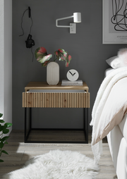 Moderne Nachtkommode mit Holzfront und schwarzem Metallrahmen, dekoriert mit einer Vase und einer Uhr, seitliche Perspektive.