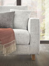 Ecksofa in hellem Stoff mit Kissen und roter Decke, seitliche Perspektive